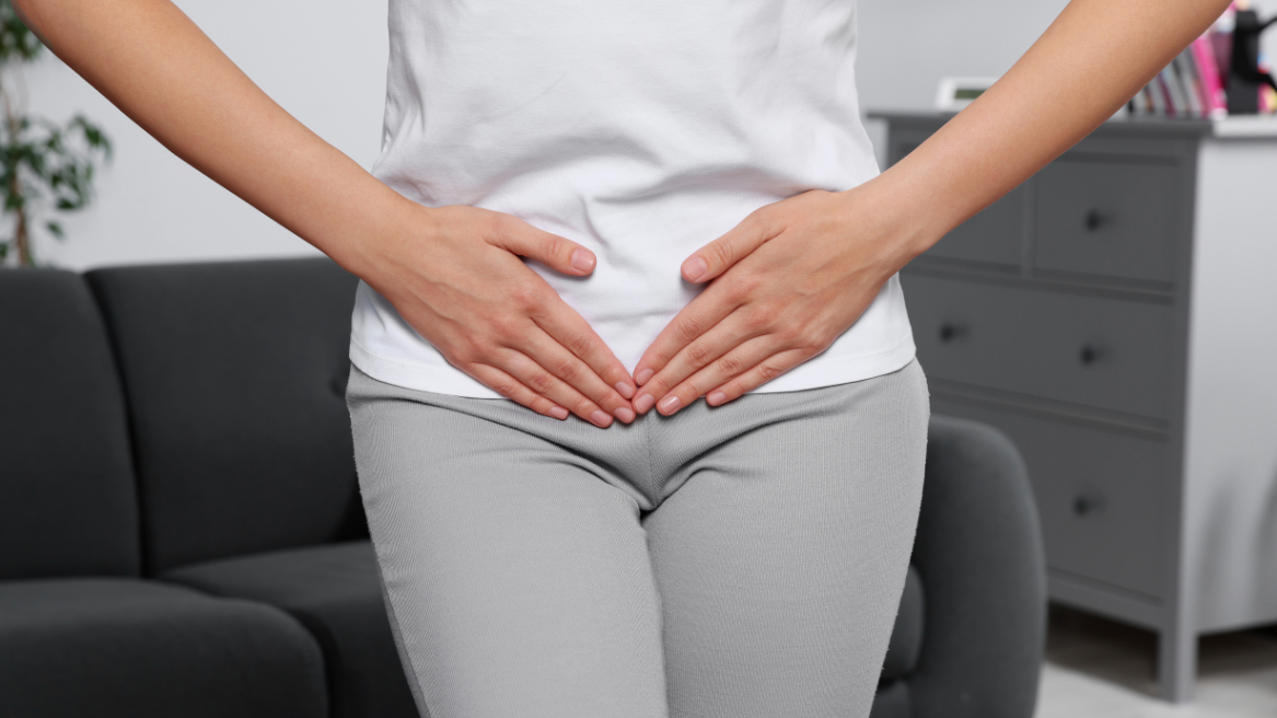 Woman holding her lower abdomen, indicating pain or discomfort associated with a urinary tract infection.